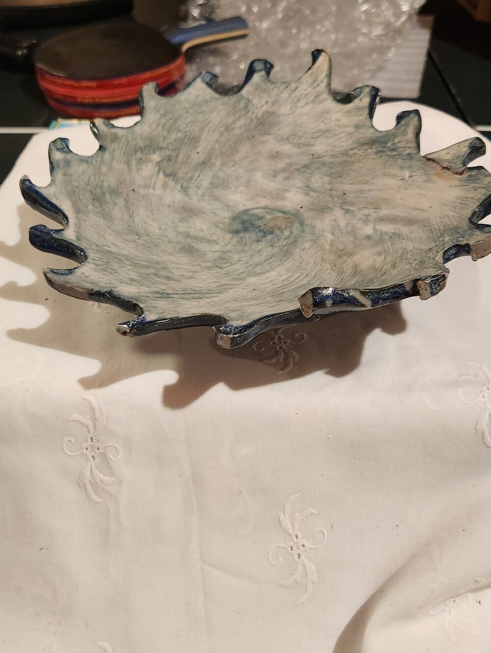 Handmade ceramic bowl with a wavy edge and a blue-and-white swirled glaze.